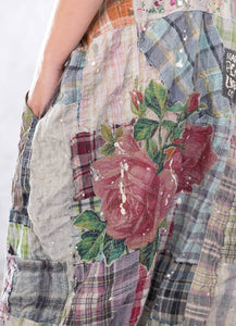 Up close view of plaid overalls with floral appliqué